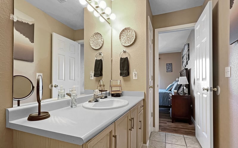 A bathroom with a sink , mirror , and cabinets.