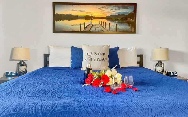 A bed with a blue blanket and a picture on the wall above it.