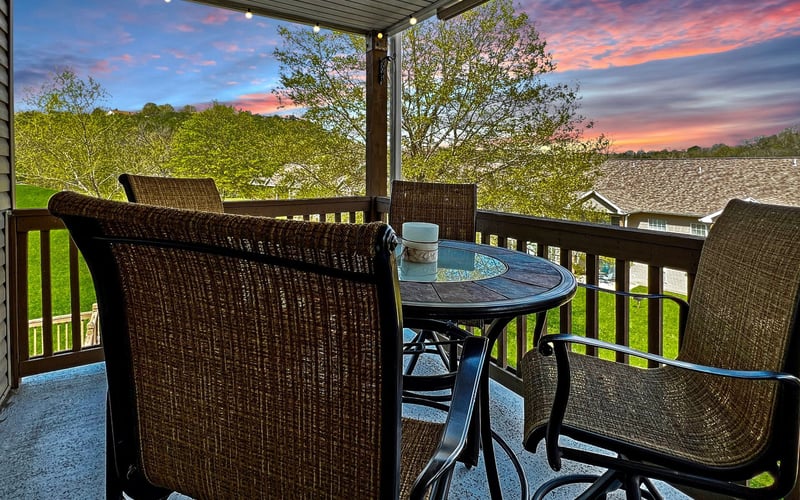 A patio with a table and chairs and a sunset in the background.