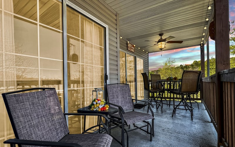 A porch with chairs , a table and a ceiling fan