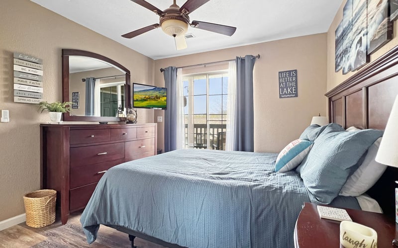 A bedroom with a bed , dresser , mirror and ceiling fan.