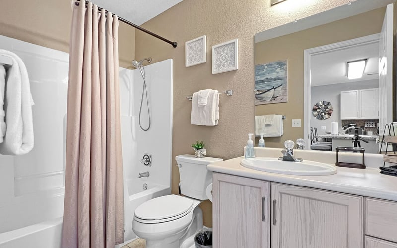 A bathroom with a toilet , sink , shower and mirror.