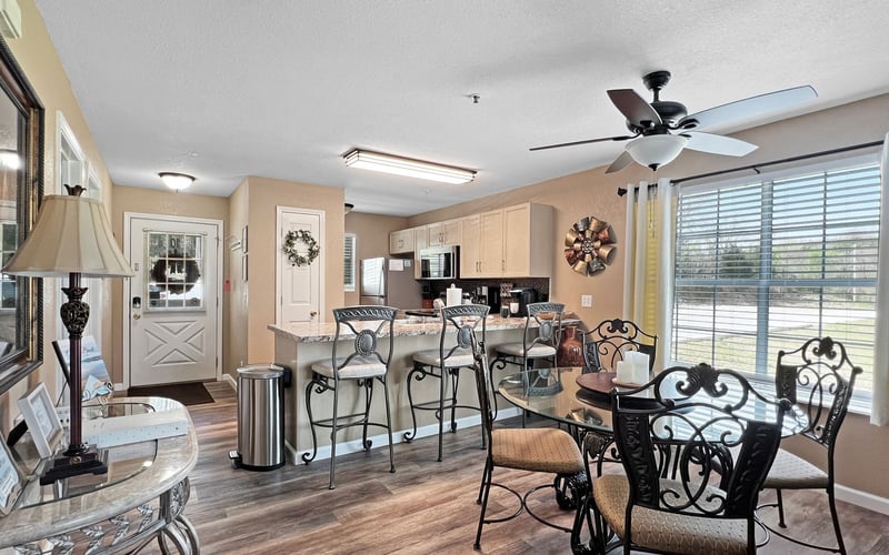 A living room with a table and chairs and a ceiling fan.