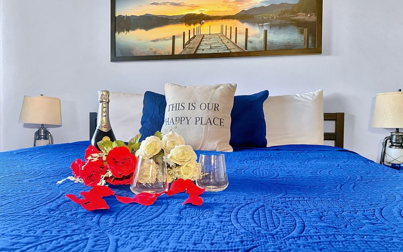 A bed with a blue blanket and a pillow that says `` this is our happy place ''.