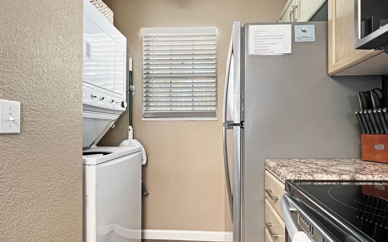 A kitchen with a washer and dryer and a refrigerator