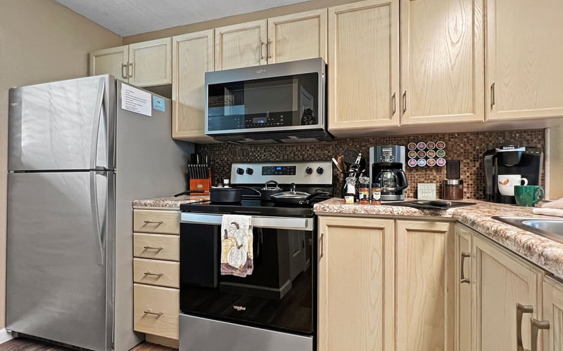 A kitchen with stainless steel appliances , a refrigerator , stove , microwave and sink.