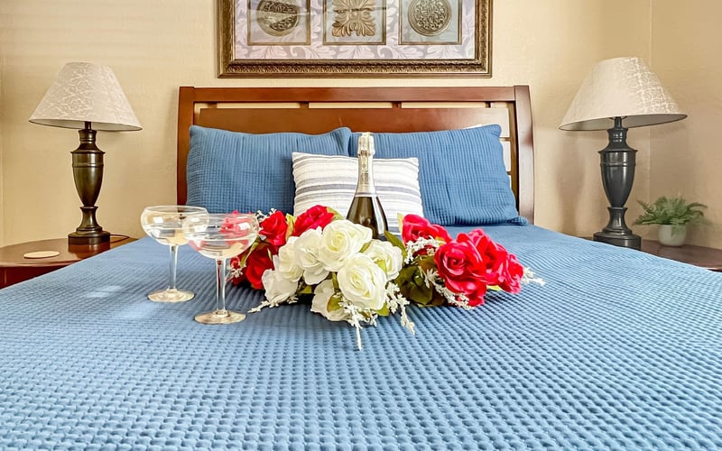 A bed with flowers and a bottle of champagne on it