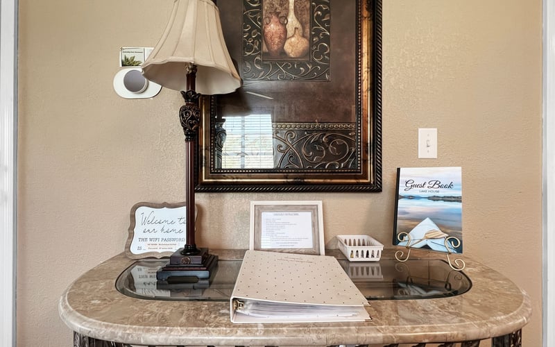 A table with a lamp and a picture on the wall.